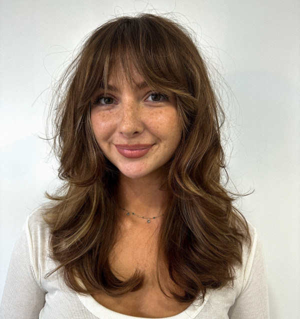 soft butterfly cut with wispy curtain bangs on brown hair with highlights